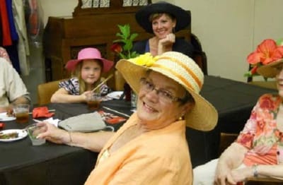 Residents enjoying a social gathering with hats and flowers