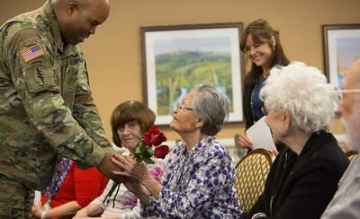 A veteran presenting roses to a resident during a celebration