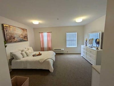 A spacious, well-lit resident room with a neatly made bed