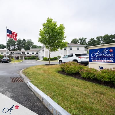 Exterior view of All American Assisted Living facility with flag