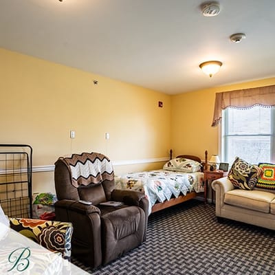 A cozy resident room with two beds and seating