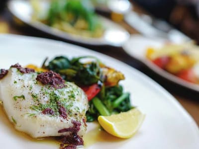 Plate of grilled fish with vegetables and lemon