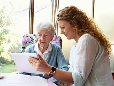A staff member assisting an elderly resident with a tablet