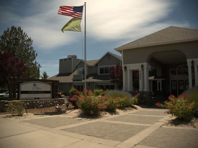 Front entrance of a senior living facility with flags and flowers