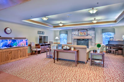 Bright common area with seating, piano, and fish tank