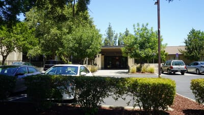 Front entrance of a senior living facility surrounded by trees