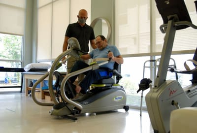 Staff assisting a resident with rehabilitation equipment
