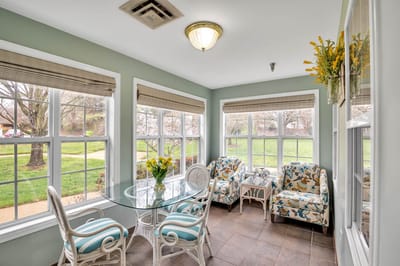 Bright sunroom with floral chairs and a table