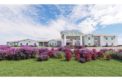Exterior view of a senior living facility surrounded by flowers