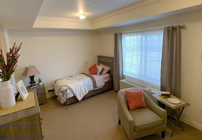 A cozy resident room with a bed and armchair