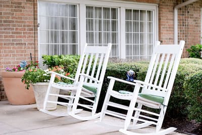 Two rocking chairs on a porch surrounded by greenery