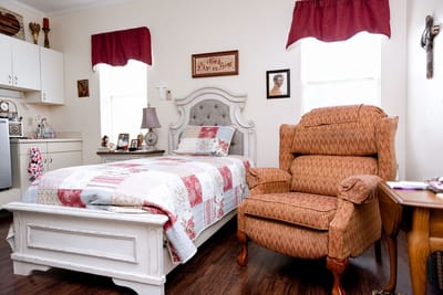 Interior view of a private resident room with a bed and armchair