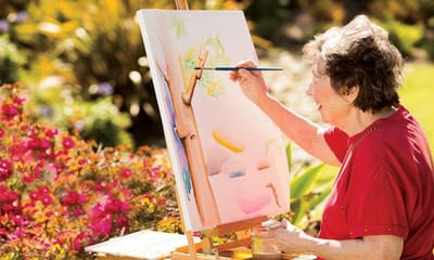 Resident painting outdoors in a garden setting