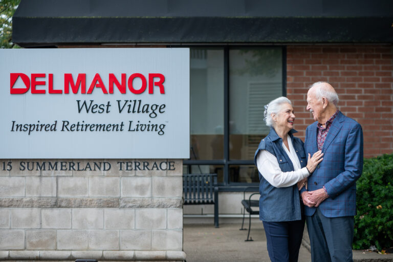 Couple smiling outside the Delmanor West Village sign