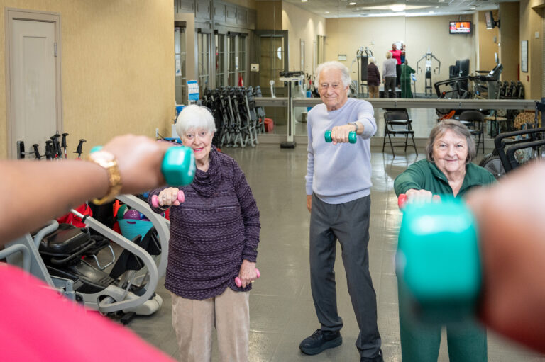 Residents participating in a group fitness activity with weights