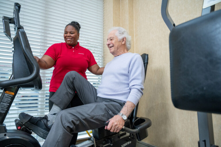Senior resident exercising with staff assistance
