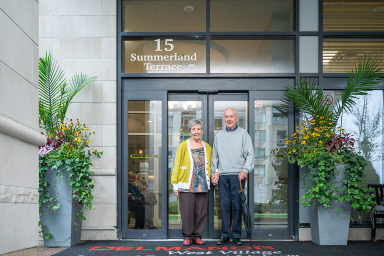 Two residents posing at the entrance of Delmanor West Village