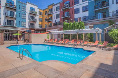 Pool area with sun loungers and colorful apartment building