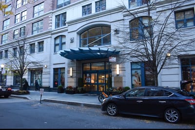 Building entrance with blue awning and parked car