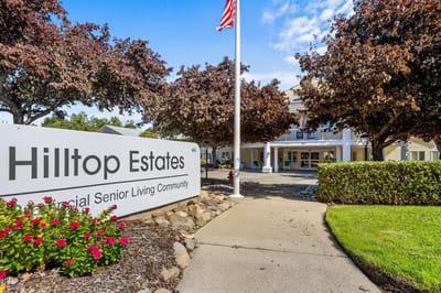 Entrance of Hilltop Estates with flower beds and American flag