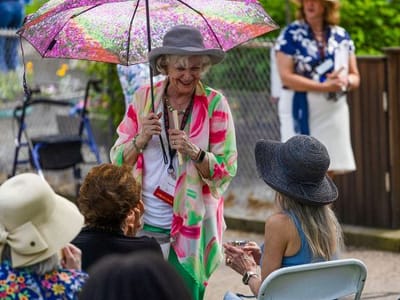 Residents engaging in an outdoor social event with umbrellas.