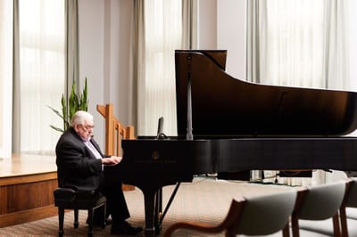 Resident playing piano in a light-filled common area