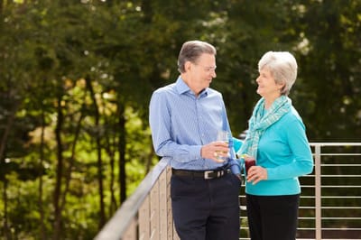 Couple enjoying drinks on a balcony surrounded by greenery