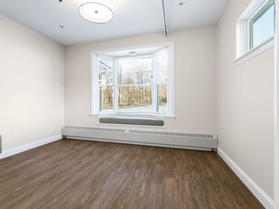 An empty interior room with large windows and wooden flooring