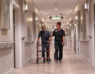 Staff member assisting a resident in a hallway