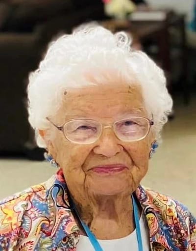 A smiling elderly resident with white hair and glasses
