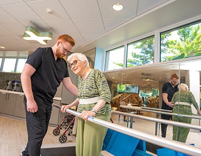 A caregiver assisting a senior resident in a therapy room