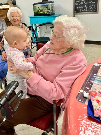 A resident holding a baby, smiling warmly