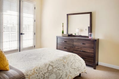 Bright, furnished resident room with a bed and dresser