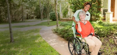 Caregiver assisting a resident in a garden path