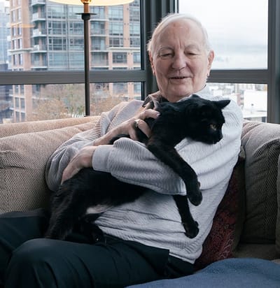 A resident smiling while holding a cat in a cozy indoor setting