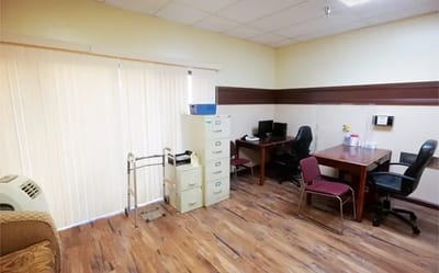 Brightly lit interior office with desks and filing cabinet