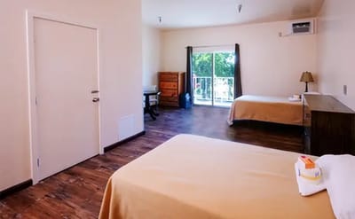 A simple shared bedroom with two beds and a balcony