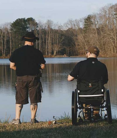 Two men fishing by a lake in an outdoor setting