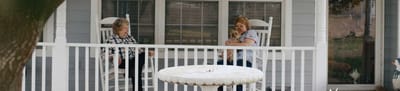 Two residents on a porch, one with a dog