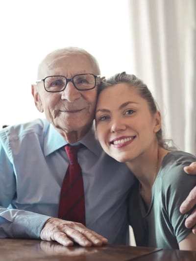 An elderly man and a young woman smiling together