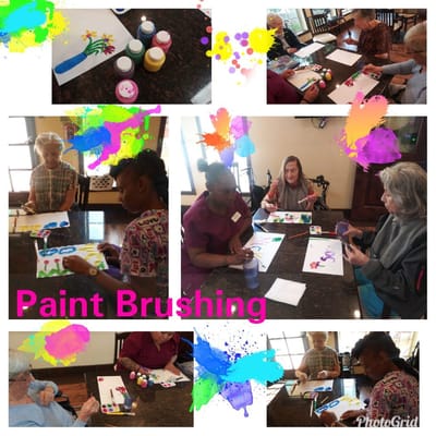 Residents painting in an activity room with staff assistance