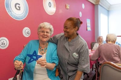 Resident playing bingo with staff in an activity room