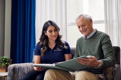 A staff member reading with a resident in a cozy interior