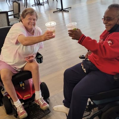 Two residents toasting with beverages in a common area