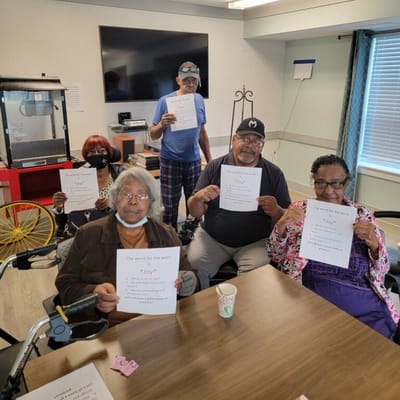 Residents participating in an activity, holding papers with words.