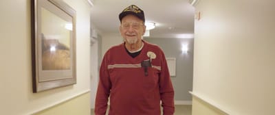 A smiling resident walking down a facility hallway