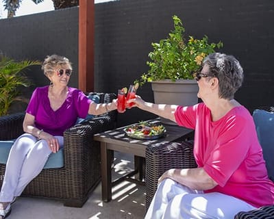 Two residents toasting with drinks in an outdoor setting
