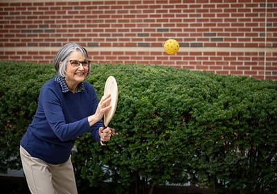 Resident playing pickleball outdoors