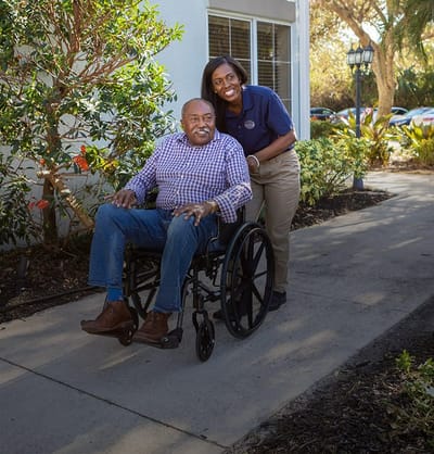 Resident in a wheelchair with a staff member outdoors