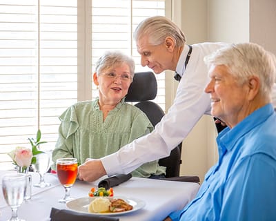 Dining room scene with residents and a waiter
